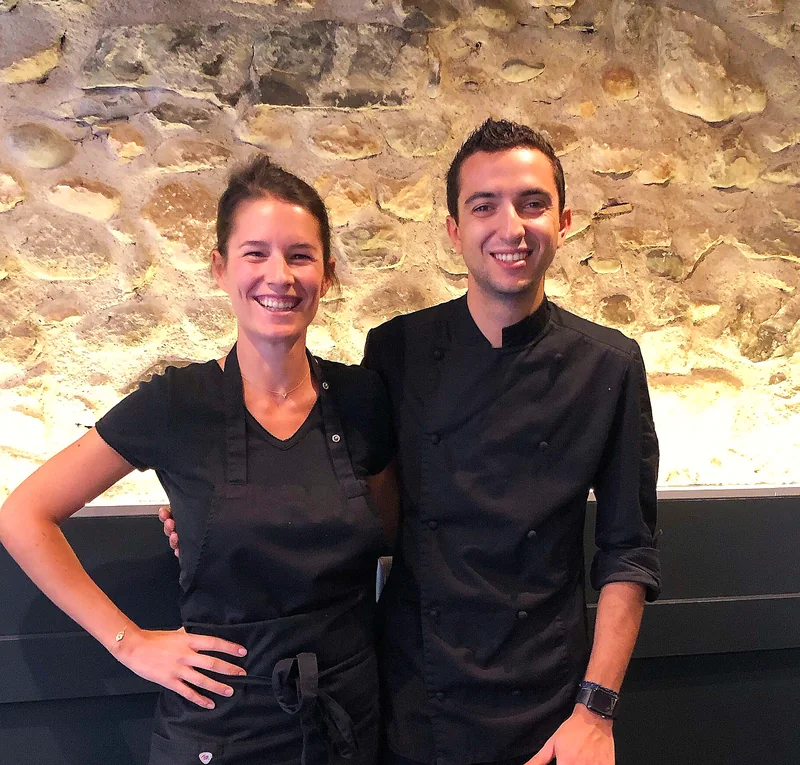 Sandra et Léo dans la salle, devant le mur de galets
